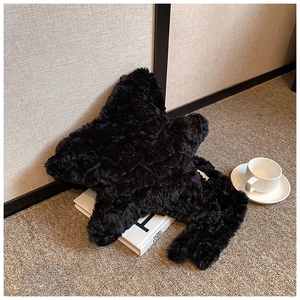 Detail of a black plush star-shaped handbag on a prop book with a coffee cup