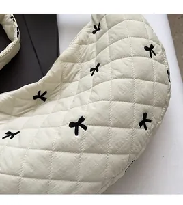 Detail of off-white quilted crescent bag with diamond stitching and black ribbon bows
