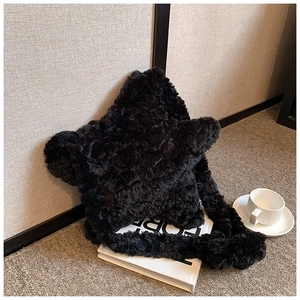 Chic black plush star-shaped shoulder bag placed on books in a cozy setting