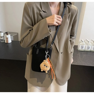 Détail du mini sac cabas noir en cuir grainé avec breloque monstre et cordon orange vif