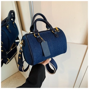Dettaglio della borsa Boston in denim blu scuro con manici in pelle e dettagli dorati