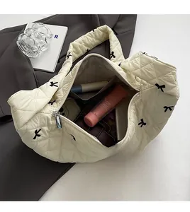 Spacious interior of a quilted off-white tote bag with black bow embroidery and zip closure