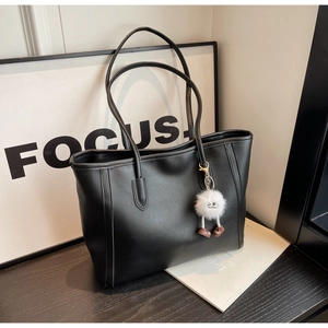 Close-up of black matte PU leather tote bag with contrast stitching and plush doll charm