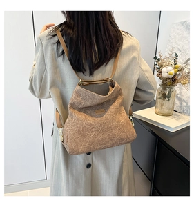 Detail of brown pleated texture backpack with metallic hooks and slim straps