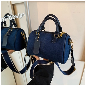 Dettaglio della borsa boston in denim blu scuro con fibbie dorate e tracolla larga