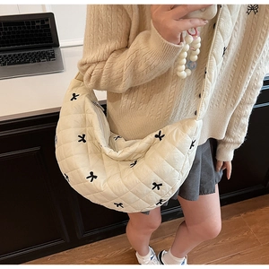 Detail of cream quilted crescent bag featuring delicate black bow embroidery