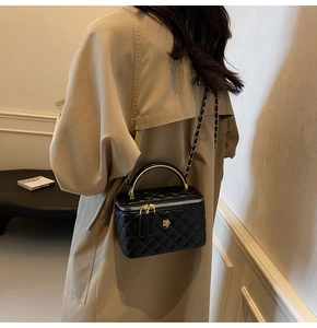 Detail einer schwarzen gesteppten Leder-Umhängetasche mit goldener Kette an einem Modell