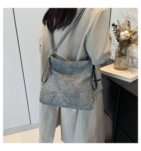 Detail of grey textured crossbody bag with unique marble pattern and golden hardware