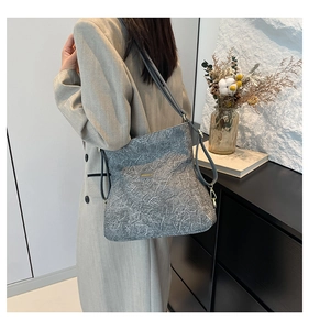 Detailed view of the gray stone-textured handbag with metallic buckles and thin straps