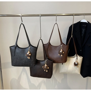 Detailed view of four soft leather tote bags in grey, brown and beige with plush charms
