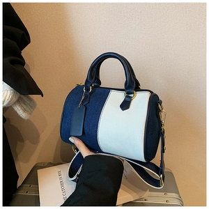 Dettaglio borsa Boston con patchwork in denim e tela, manici in pelle e finiture dorate