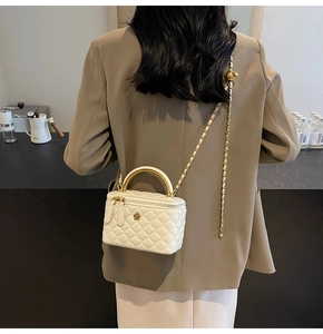 Nahaufnahme der beigen gesteppten Vanity Bag mit Goldgriff und Blumenverschluss