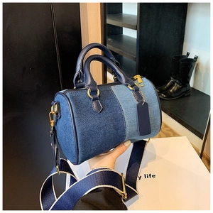 Dettaglio borsa Boston in denim patchwork con manici in pelle e tracolla larga