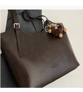 Detailed close-up of retro brown tote bag with quilted texture and plush toy pendant