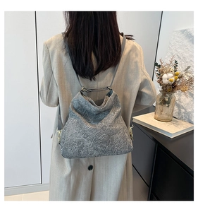 Detail view of the gray textured backpack showing the shoulder straps and side metal buckle