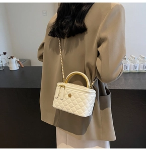 Detailansicht einer weißen Stepptasche mit goldenem Blumenlogo und Kettenriemen