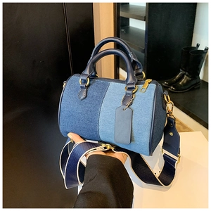 Dettaglio della borsa Boston in denim patchwork con tracolla a righe e finiture dorate