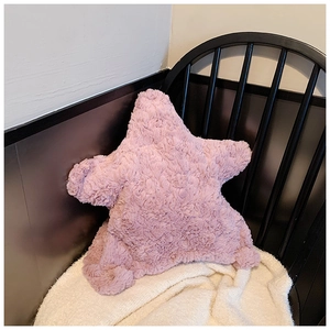 Detailed view of pink star-shaped plush shoulder bag on a stylish wooden chair