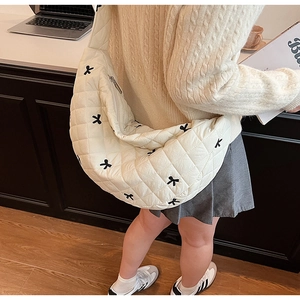 Detailed close-up of white quilted crescent bag with delicate black bow embroidery accents