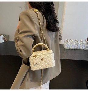 Detailansicht der cremefarbenen Stepptasche mit goldenem Griff an der Schulter