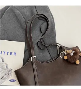 Detailed view of dark brown vintage leather tote with adjustable strap and cute monster charm