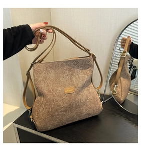 Detailed macro view of brown textured tote bag with premium leather straps and logo plaque