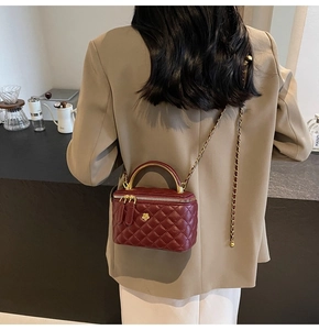 Detailansicht der weinroten gesteppten Mini-Box-Tasche mit Goldgriff und Kettenriemen