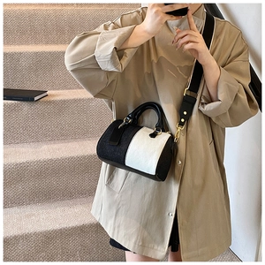 Dettaglio borsa Boston bicolore con tracolla larga indossata su un cappotto beige