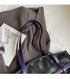 Detail of purple faux leather strap and black croc-effect texture on shoulder tote bag