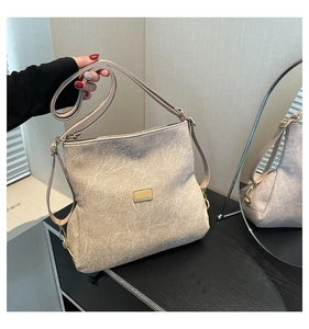Detailed view of the beige textured leather bag and adjustable shoulder strap with gold hardware