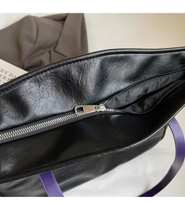 Detail of smooth silver zipper and purple strap on black PU leather shoulder bag