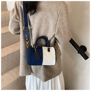 Dettaglio borsa a cilindro blu e beige con tracolla in tessuto e finiture metalliche oro