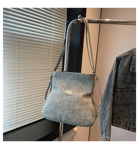 Detail of light grey marbled crossbody bag with gold hardware and logo plaque