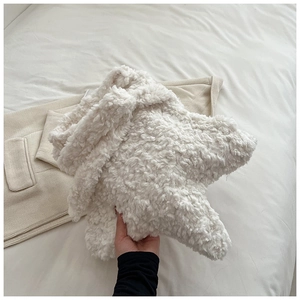 Close-up of white star-shaped plush bag in soft faux shearling held for size reference