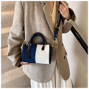 Dettaglio borsa Boston in tela blu scuro e beige con manici in pelle e tracolla