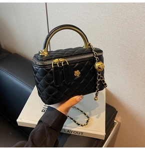 Nahaufnahme einer schwarzen Steppleder-Kosmetiktasche mit Goldgriff und Blumendeko