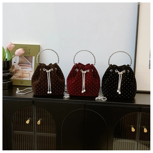 Detail of velvet drawstring bucket bags in burgundy, brown and black with pearl accents
