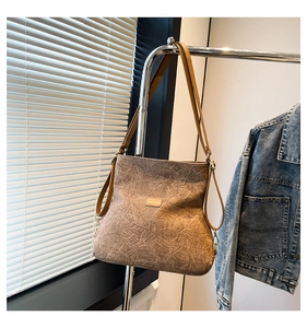 Detail shot of a brown textured crossbody bag with vintage pleated leather and metal strap