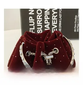 Close-up of burgundy velvet bucket bag with crystal accents and metal chain details