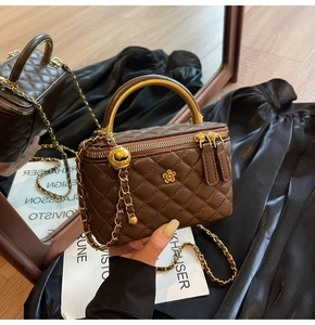 Detail der dunkelbraunen Stepptasche mit goldenem Blumenschloss und Metallgriff