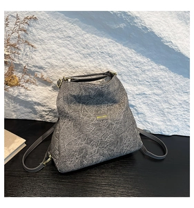Detail of dark grey textured bucket bag with metallic hooks and minimalist styling