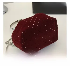 Detail of burgundy velvet bucket bag with silver studs and wavy metal handle