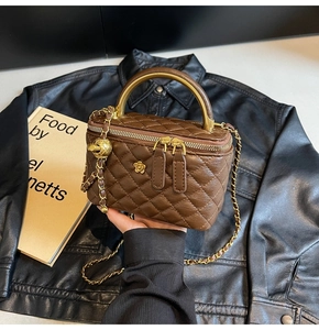 Detailansicht der braunen gesteppten Box-Tasche mit goldenem Griff und Kette
