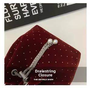 Detail of burgundy velvet bucket bag with silver studs, chain drawstring and pearl accents