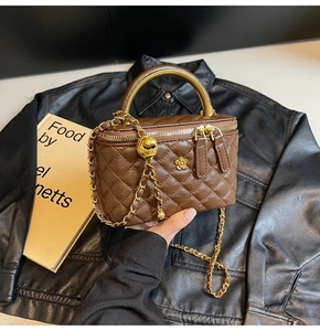 Detaillierte Nahaufnahme der braunen Stepptasche mit goldener Blume und Metallgriff