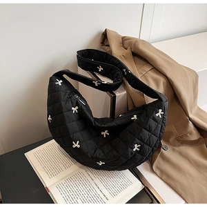 Detail of black quilted crescent bag with bow accents on vintage book background