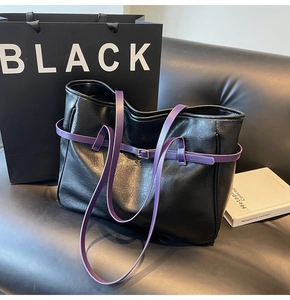 Detail of black matte leather tote bag featuring striking purple shoulder straps and buckle