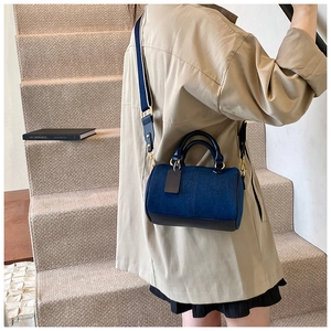 Borsa Boston in denim blu e pelle nera con tracolla a righe indossata da modella