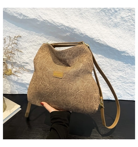 Detailed shot of the brown textured tote bag with brand logo and leather straps