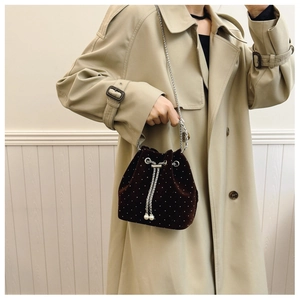 Detail of a dark brown velvet bucket bag with beaded dots and a silver chain strap